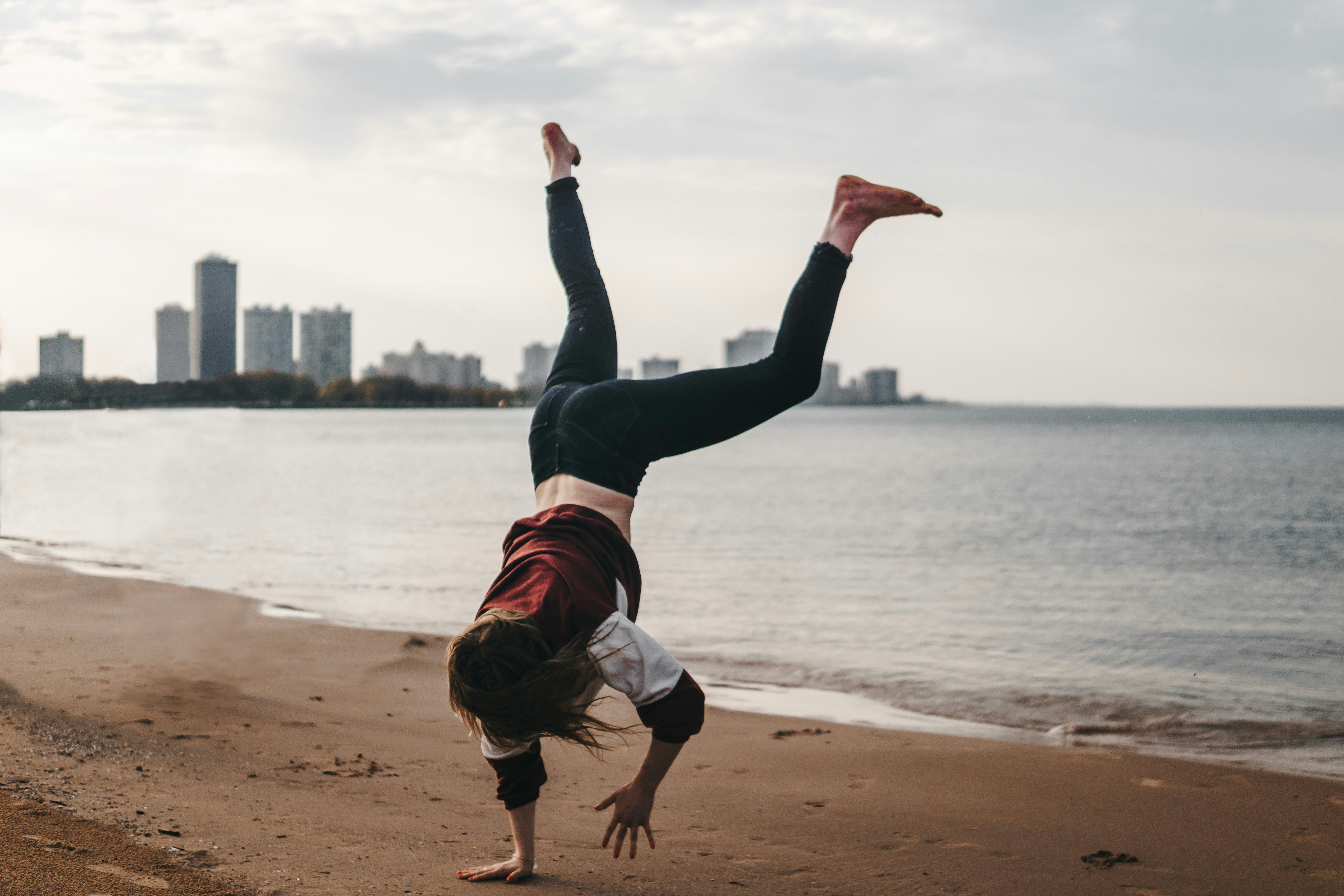 woman in black pants and white shirt jumping on beach during daytime